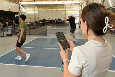 Organizer holding smartphone using the fairplay pickleball app checking for next players.